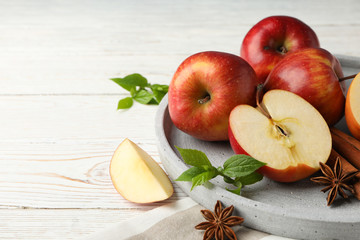 Tray with apple and cinnamon, and towel on wooden background, close up