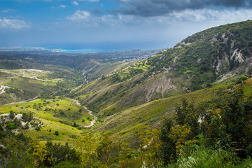 Naklejka premium Spectacular panoramic view of beautiful green calming landscape of Mediterranean valley below clean blue cloudy sky. The city of Paphos on the horizon
