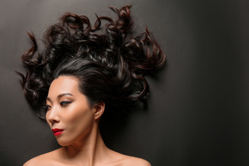 Fototapeta premium Young Asian woman with beautiful hair on dark background