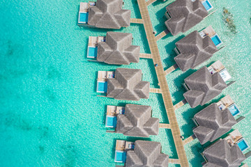 Aerial view of resort water bungalows and villas. Luxury over water villas with private pools with amazing coral reef and blue sea