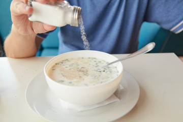 He eats soup okroshka from round white plate