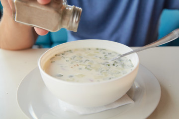 He eats soup okroshka from  round white plate