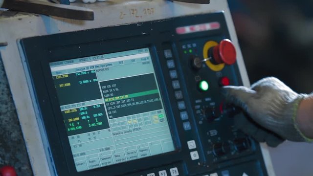 Factory worker is programming a CNC milling machine. Metalworking milling machine. Produces metal detail in a factory. A metal workpiece is machined by an electric machine.