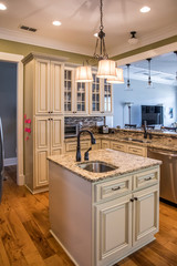 A square shaped green kitchen with cream colored cabinets in a new construction home with granite...