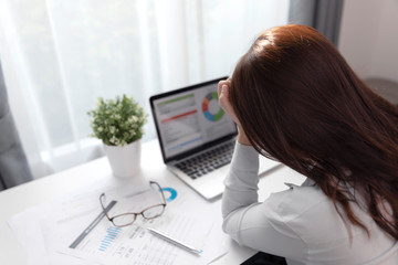 Young business frustrated woman working at office desk in front of laptop suffering from forehead feeling stressed out.