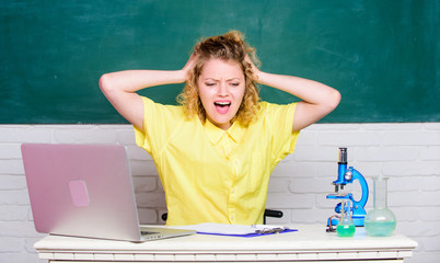 Stressful day. Stressful student life. Girl emotional with laptop and microscope working on own...