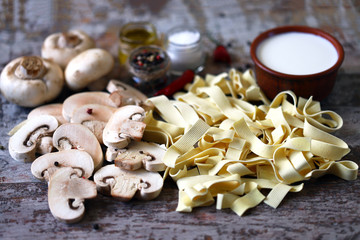 Raw pasta, mushrooms, cream and spices. Products for the preparation of mushroom pasta with cream. Mushrooms pasta recipe.