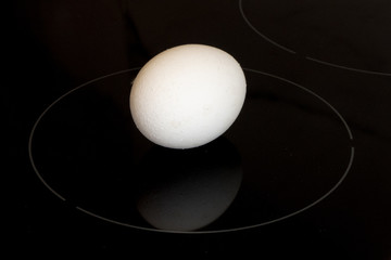 Minimalistic futuristic white chicken egg on black cooktop