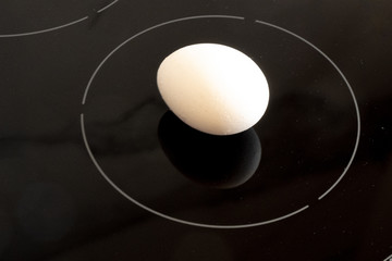 Minimalistic futuristic white chicken egg on black cooktop