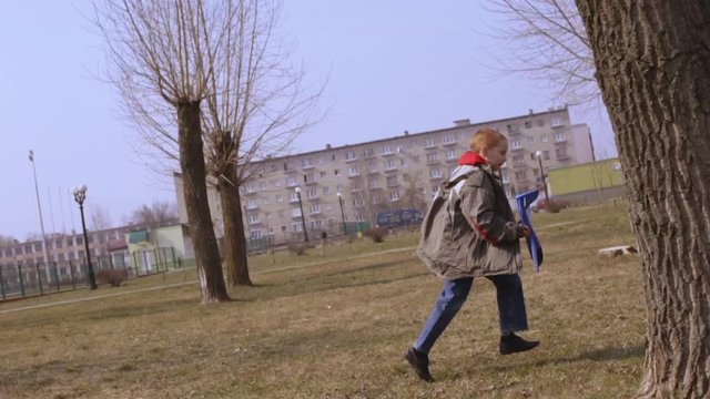 Joyful boy playing with toy airplane. Side view of smiling child running on green grass in park and throwing foam plane