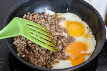 The chef prepares Breakfast. Boiled buckwheat and fried two eggs in the pan