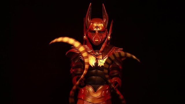 4k video clip, on a black background, a male actor in a suit of an Egyptian mythology character, the golden deity Jackal Anubis, twists buugeng in red light.