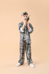 Cute little soldier with walkie-talkie on color background