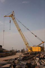 A large yellow crane stands on the basis of rolled metal
