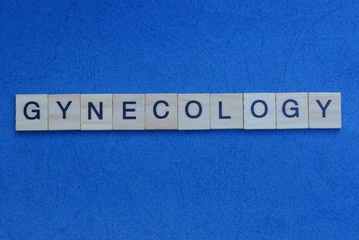 gray word gynecology from small wooden letters on a blue table