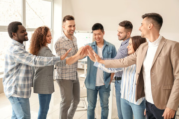 Group of people putting hands together indoors. Unity concept