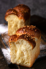 soft brioche broken in half, on a wooden board