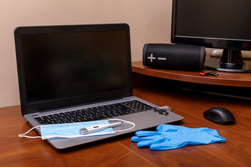 Home office theme. Stayathome during coronavirus pandemic. Ncov COVID-19 concept. Laptop or computer with protection glove and mask.