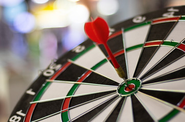 Close up shot red dart arrow on center of dartboard