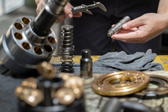 Professional mechanic man holding Valve rod of the hydraulic piston pump to inspection and repair maintenance heavy machinery