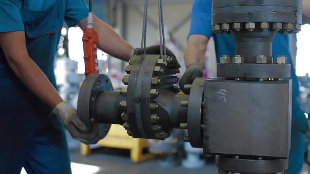 Oil and Gas Wellhead tree equipment production plant. Worker assembles of wellhead fitting. Modern tendencies of machine engineering. Equipment for wellhead conncetion of oil and gas wells.