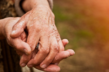 Fototapeta premium Hands of an old grandmother in a mile close-up. Grandmother disinfects her hands with soap due to an outbreak of coronavirus and a large number of infected