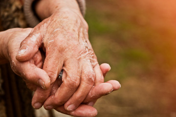 Hands of an old grandmother in a mile close-up. Grandmother disinfects her hands with soap due to an outbreak of coronavirus and a large number of infected