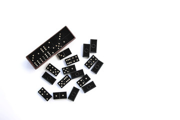 Fototapeta na wymiar Heap of vintage black domino tiles and dominoes in the box on light background
