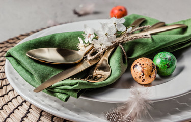 Easter table setting. Empty plates with green linen napkin and golden cutlery on concrete background. Top view. Flat lay. Copy space.