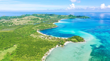 Fototapeta na wymiar A lagoon with a coral reef and a white sandy beach, aerial drone. The coast of a tropical island. Caramoan Islands, Philippines. Summer and travel vacation concept.