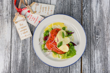 Salad with cheese and tomatoes on wooden background. The view from the top