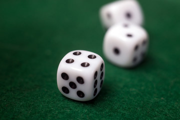 Closeup of white dices on green carpet background