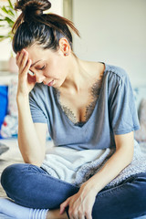 Fototapeta premium Sick woman sitting in bed with flu and huge headache.