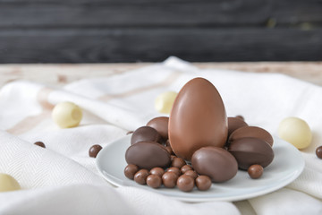 Plate with chocolate eggs and candies on table