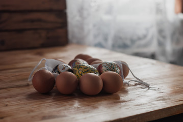 Easter eggs and a medical mask on a wooden table in the early morning. The concept of the Feast during the plague,