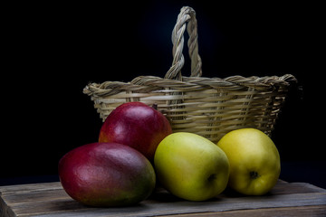 mangoes and yellow apples with a basket of natural cane