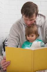 Father reading the book with his little daughter. Family time.