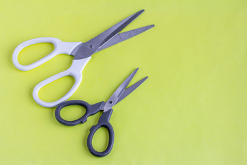Scissors on a yellow background.White large and black small scissors for work and creativity.