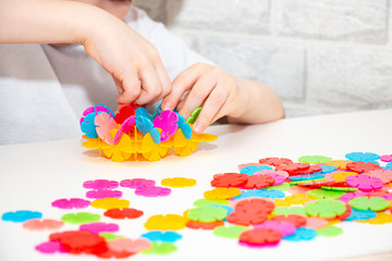 A child in bright clothes plays a developmental game with multi-colored circles. Early childhood development. Home leisure.