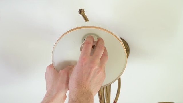 electrician installs and mounts the chandelier on the ceiling in the room, after installing the stretch ceiling.