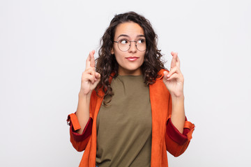 young pretty woman crossing fingers anxiously and hoping for good luck with a worried look against...