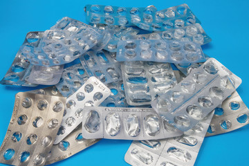 Many empty blister packs without pills on blue background. Medical and healthcare concept.