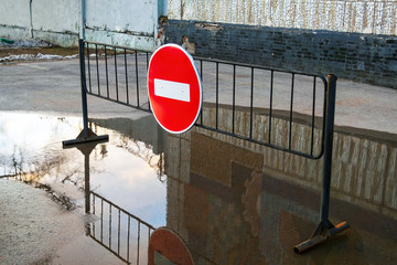Road sign No entry for vehicular traffic on metal stand in puddle near building.