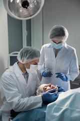 Doctor and nurse preparing female patient for cosmetic surgery in clinic