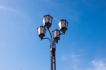 one large vintage lamppost closeup against a blue sky