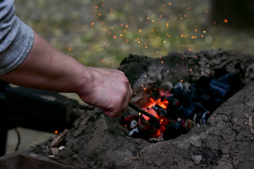 The working hand of a blacksmith tedding coals in an iron forge 