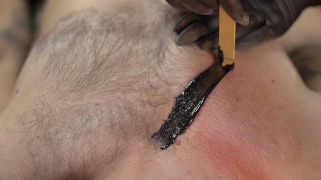 Hairy male chest and black wax for depilation. Male waxing depilation