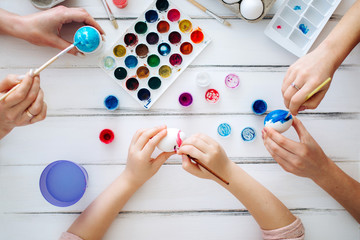 Close up female hands blue Easter eggs White background. Flat lay Home tradition of painting eggs