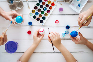 Close up female hands blue Easter eggs White background. Flat lay Home tradition of painting eggs