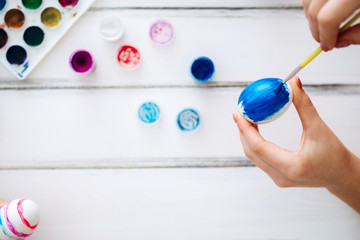 Close up female hands blue Easter eggs White background. Flat lay Home tradition of painting eggs